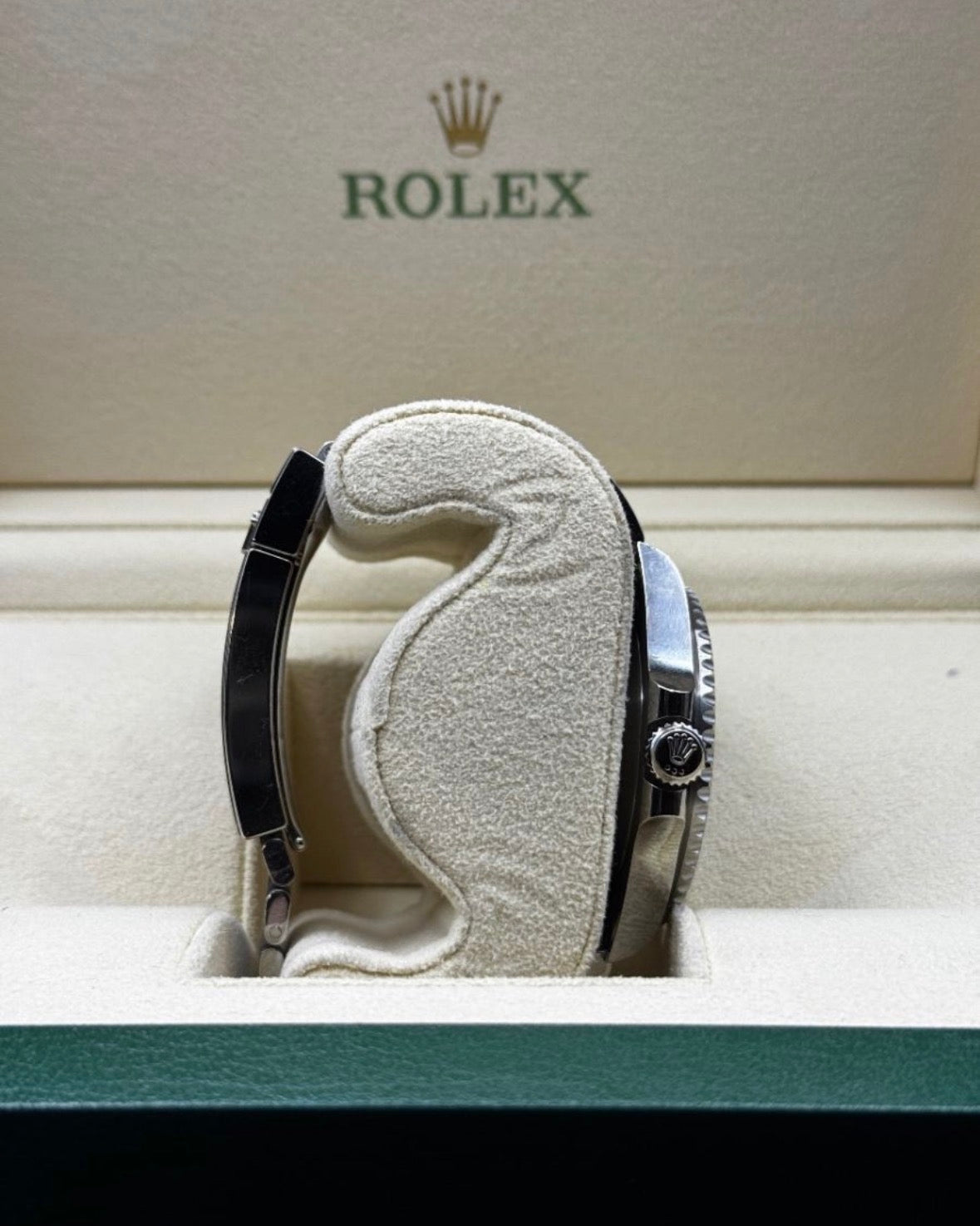Rolex watch on a cushioned stand with Rolex logo in the background