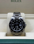 Rolex watch with black dial and silver case on a display stand