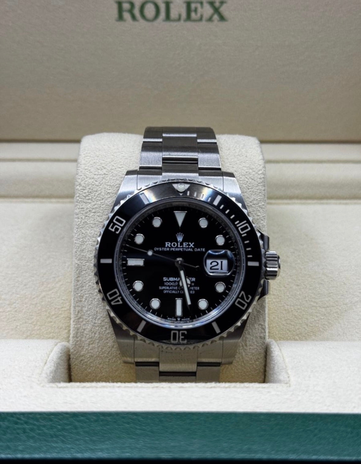 Rolex watch with black dial and silver case on a display stand