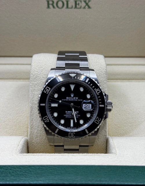 Rolex watch with black dial and silver case on a display stand